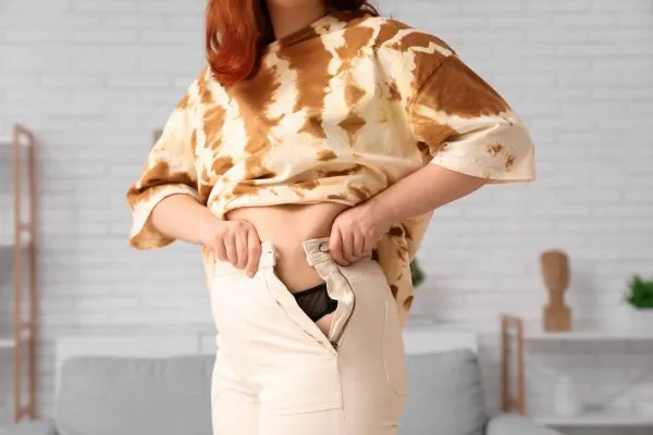 Image of woman trying to do her trousers up after pregnancy weight gain Bloxwich